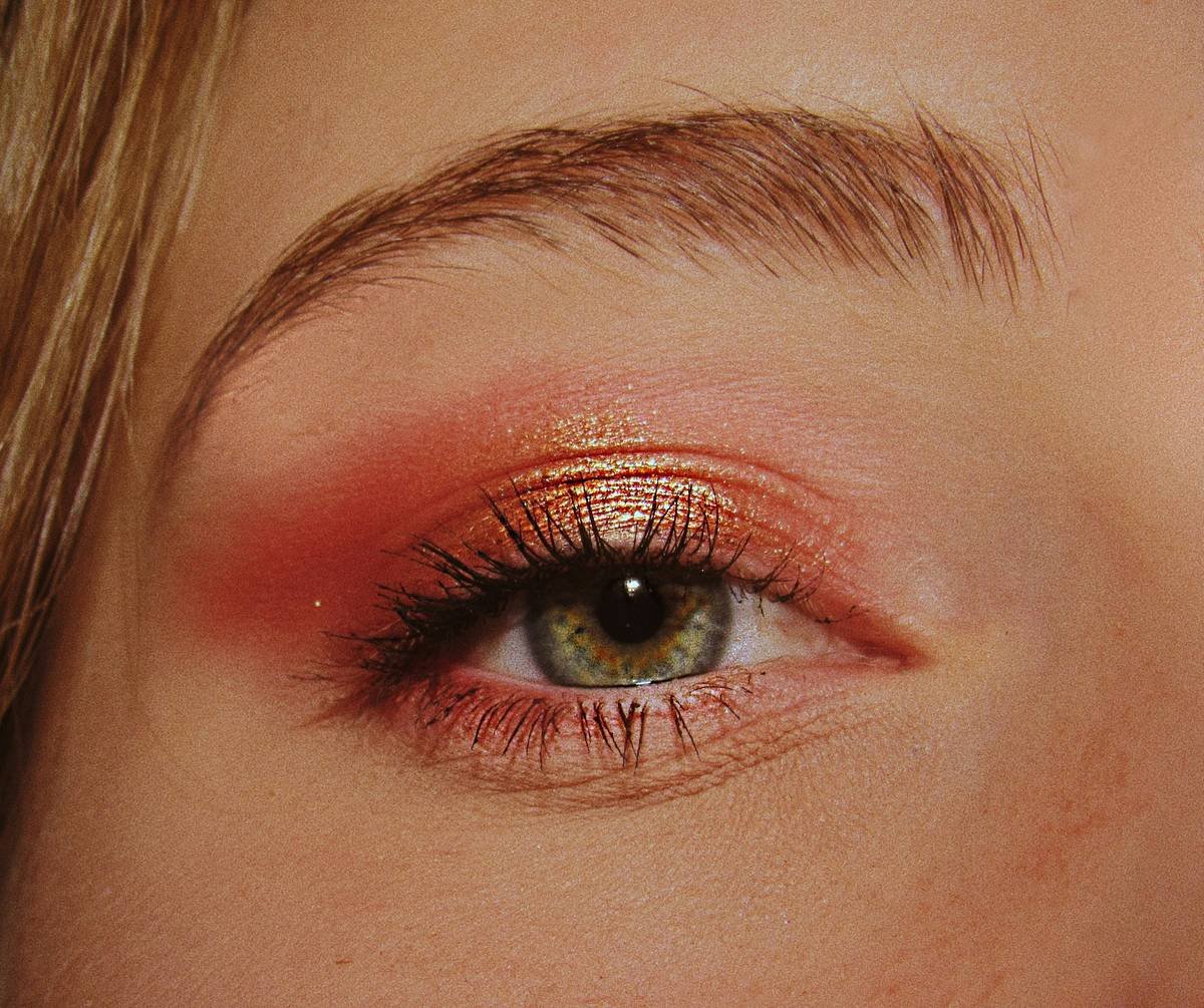 Infographic showing layers of surreal eye makeup: primer base, pigment sealant, sculptural adhesive, and top gloss coat with material callouts